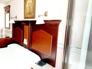 萨拉曼卡Hosteria Sara by gaiarooms的一间卧室配有一张床和一个木制床头板