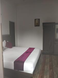 蒙纳Landy Queen的卧室配有白色的床和紫色毯子