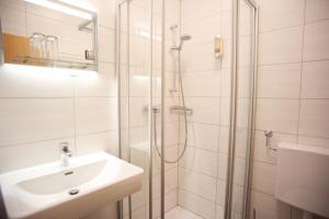 滨湖波德斯多夫Gasthof Kummer的带淋浴和盥洗盆的白色浴室