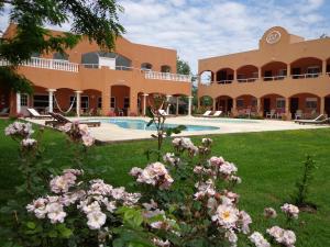 圣米格尔-德尔蒙特Las Victorias Apart Hotel的庭院里一座带游泳池和鲜花的建筑
