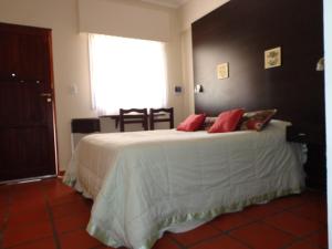 圣米格尔-德尔蒙特Las Victorias Apart Hotel的卧室配有带红色枕头的大型白色床