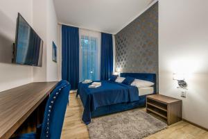 普雷绍夫Hotel Black Horse的酒店客房配有蓝色的床和电视。
