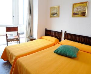 圣卡洛斯拉腊皮塔坎玛丽尼斯旅馆的配有黄色床单的酒店客房的两张床