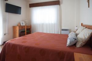 ArcozeloApartamentos Turisticos Ceu Azul的一间卧室配有一张带橙色毯子和窗户的床。