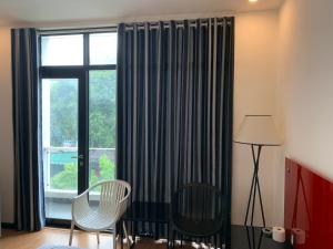 胡志明市Gia Huyền Hotel的客房设有带椅子和灯的大窗户。