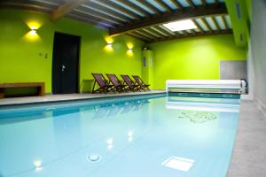 RochessonGite Roche Des Ducs avec Piscine toute l'année, Spa, Sauna, Hammam的一个带椅子的游泳池,位于带绿色墙壁的房间