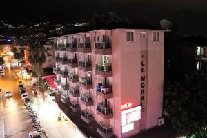 阿拉尼亚Le Moral Apart Hotel的夜晚在城市街道上一座粉红色的建筑