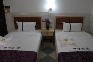西哈努克Don Bosco Guesthouse的两张睡床彼此相邻,位于一个房间里