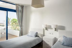 普拉亚布兰卡Villas de la Marina的一间白色卧室,配有两张床和一个阳台
