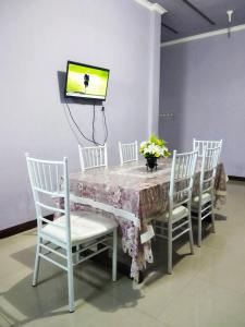 特尔纳特岛古妮亚民宿的一张桌子、白色椅子和墙上的电视