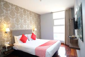 关丹Super OYO 546 Grand City Hotel的酒店客房配有一张带红色枕头的大床