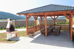 Donji Babin PotokBig Bear Plitvice Nature Resort的木制凉亭配有2张长椅和炉灶