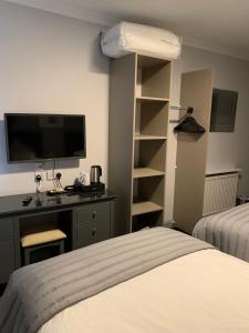 斯特兰拉尔The Royal Hotel的一间卧室配有一张床、一张书桌和一台电视。