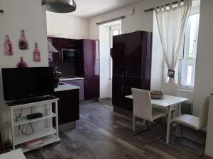 勒沙托多莱龙Ma Maison的厨房配有紫色橱柜、桌子和电视。