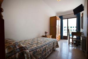 圣埃乌拉利亚萨罗塔旅馆的一间卧室设有一张床、一台电视和一个窗口。