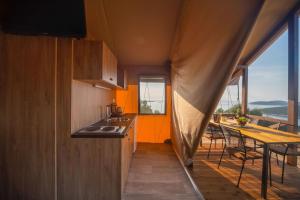 大洛希尼Glamping Tents and Mobile Homes Trasorka的厨房设有橙色墙壁和桌椅
