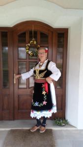 弗尔尼亚奇卡矿泉镇Apartmani Nik Lux的身穿传统服装的女人站在门前