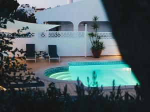 卡武埃鲁维温达布里托酒店的一个带两把椅子的游泳池以及一座房子