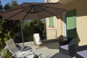 贝尔戈代尔La Villa Volpaso的阳台的天井配有遮阳伞和椅子