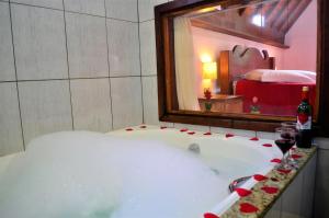 蒙特韦尔迪Chalés Fazenda Vale da Mata的浴缸位于带镜子的房间内