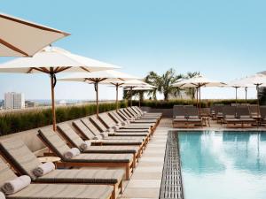 洛杉矶Santa Monica Proper Hotel, a Member of Design Hotels的游泳池旁的一排躺椅和遮阳伞