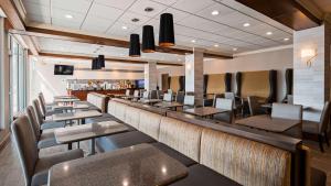 路易斯威尔Best Western Premier Airport/Expo Center Hotel的餐厅设有长长的酒吧,配有桌椅