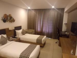 AttingalHOTEL SAVITHRI的酒店客房设有两张床和电视。