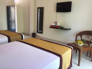 锡吉里亚Organic Garden Resort Sigiriya的酒店客房设有两张床和一台墙上的电视。