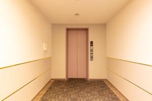 鸟栖市Sun Hotel Tosu Saga的空房间中一个空的走廊,有粉红色的门