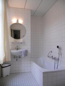 希斯特尔坦普特酒店的白色瓷砖浴室设有浴缸和水槽