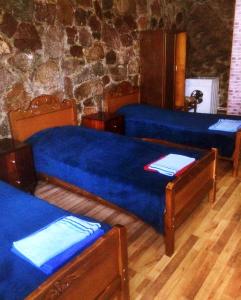 瓦尔齐亚SADA Guesthouse的石墙客房中的两张带蓝色床单的床