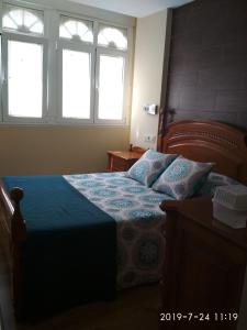 费罗尔Km 0 Camiño Ingles Benito Vicetto, 14的一间卧室配有一张蓝色棉被和两个窗户。