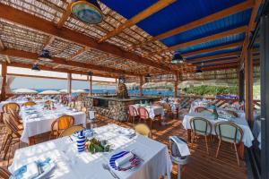 马萨鲁布朗斯罗司考格里奥酒店的海滩上的餐厅,配有白色的桌椅