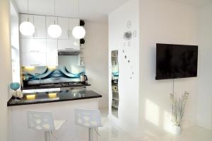 格涅兹诺Apartament Domi的一间厨房,配有白色橱柜和墙上的电视