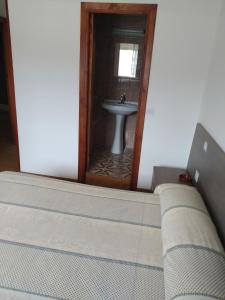 里瓦德奥HOSTAL RESIDENCIA PRESIDENTE的配有水槽和镜子的客房内的一张床位