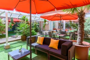 图卢兹馨乐庭图卢兹威尔逊酒店的天井配有沙发、桌子和遮阳伞