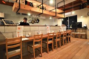 名古屋駐車場無料 Nagoya Hostel The Three Smiles Free Car Park的站在餐厅酒吧后面的人