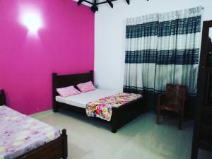 尼甘布Ahasna Family Villa的一间卧室设有两张床和粉红色的墙壁