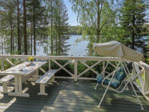 MeltausHoliday Home Sipukka by Interhome的湖畔甲板上的野餐桌和椅子