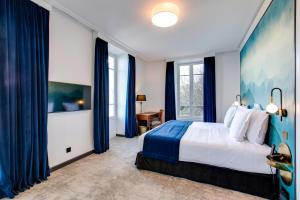 芒通圣贝尔纳门冬帕拉斯酒店的一间卧室配有一张带蓝色窗帘的大床
