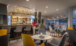 科克Maldron Hotel South Mall Cork City的一间带桌椅的餐厅和一间酒吧