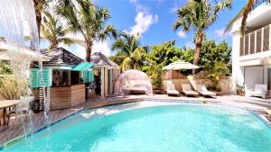 古斯塔维亚昂迪尼斯海滩酒店的房屋旁的游泳池配有椅子和遮阳伞