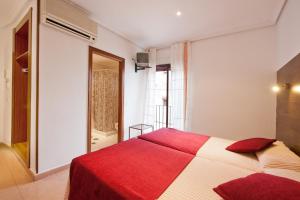 托莱多索尔旅馆的卧室设有红色和白色的床和窗户。