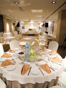 麦纳麦K酒店的一张桌子、白色的桌布和椅子以及一间房间