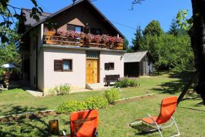 RudanovacHoliday Home "Iris" near Plitvice Lakes的庭院内带橙色椅子的阳台的房子