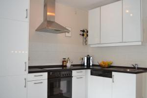 维林根Kurpark Maisonnette Willingen的厨房配有白色橱柜和炉灶烤箱。