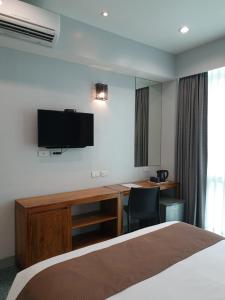 马尼拉Leez Inn Makati的酒店客房设有一张床、一张书桌和一台电视机。