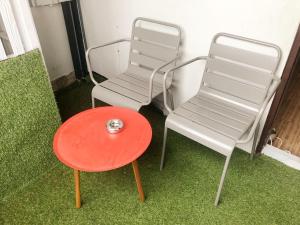 曼谷GN豪华旅舍的桌子旁的两把椅子和一把红色凳子