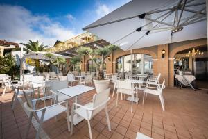 卡奥莱Park Hotel Pineta的餐厅内带白色桌椅的庭院
