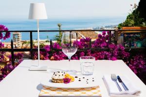 陶尔米纳陶尔米纳别墅酒店的一张桌子,上面放着一盘食物和一杯葡萄酒
